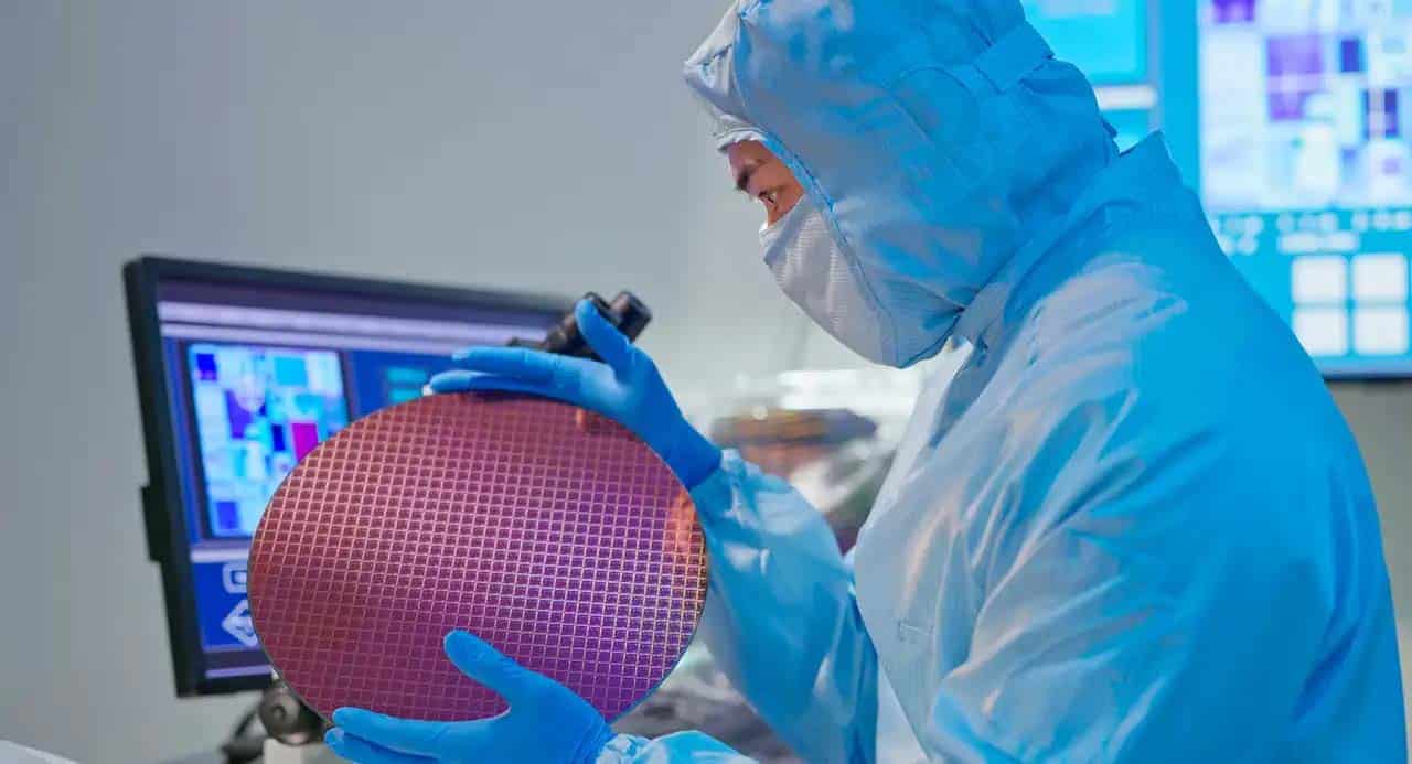 A scientist in a lab coat holds a large piece of silicon