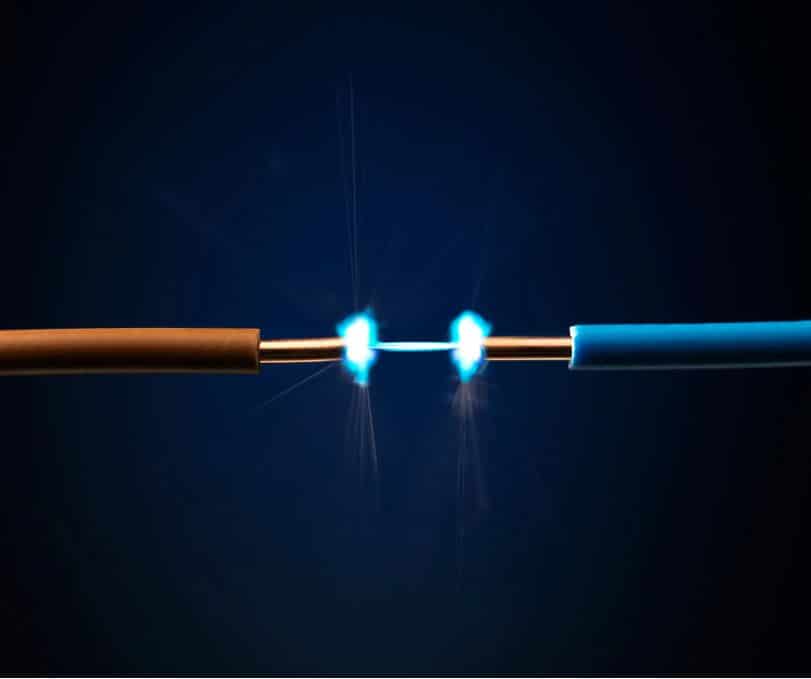 Two wires connected with blue light, creating an electrical connection