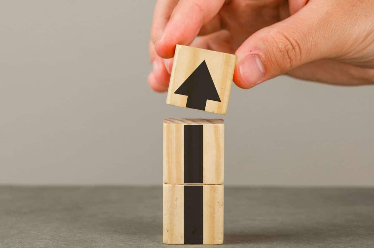 A person holding wooden blocks with arrows on them, indicating direction and guidance
