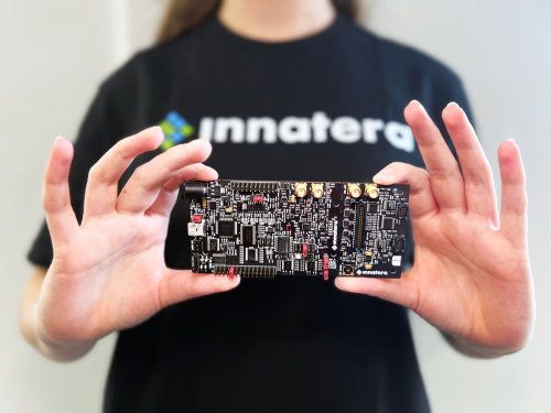 A person wearing a T-shirt that says Innatera holding up a neuromorphic processing chip