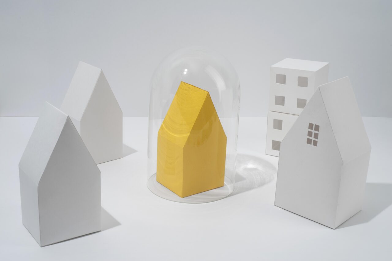 Yellow house under dome with paper houses, representing community and unity